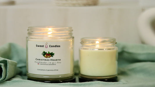 Two lit Sweet U Candles soy candles glowing warmly on a soft sage green cloth, set for a cozy evening wind-down ritual